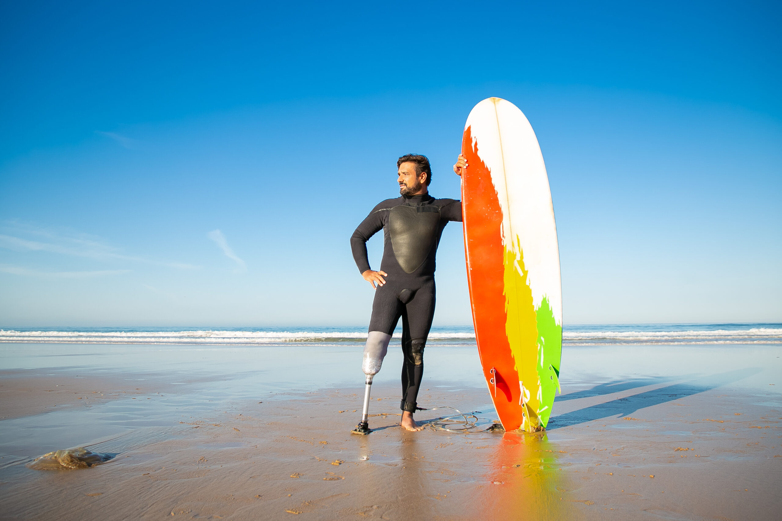 Homme en situation de handicap avec une planche sur la plage
